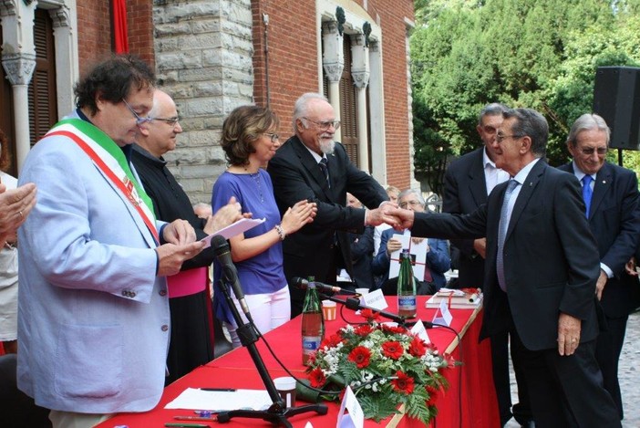 Pietro Magistrelli ritira la civica benemerenza nel 2014 (foto Città di Busto Arsizio). Sotto con l'allora assessore ai Servizi sociali Miriam Arabini