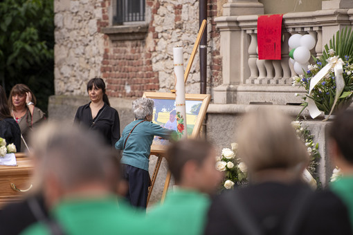 Una delle nonne di Christian accarezza un'ultima volta l'immagine del nipote prima del funerale all'oratorio di Brenno Useria (foto Alessandro Galbiati)