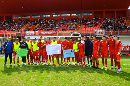 Il Varese in campo con i cartelli preparati dai bimbi ricoverati nella pediatria dell'ospedale di Circolo, a cui poi dedica la vittoria (foto Ezio Macchi)